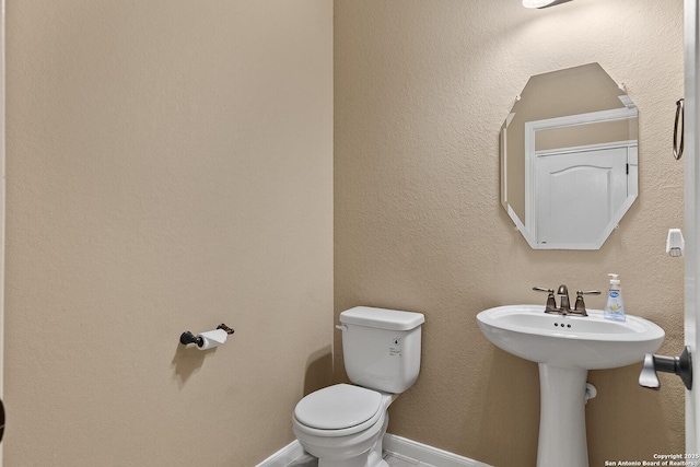 bathroom featuring toilet and baseboards