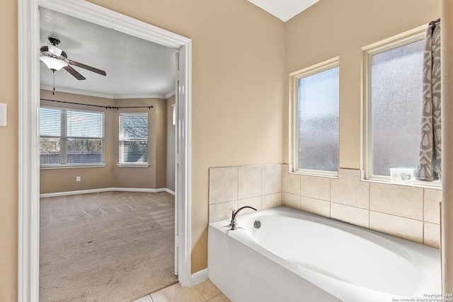 bathroom with tile patterned floors, crown molding, baseboards, a bath, and a ceiling fan