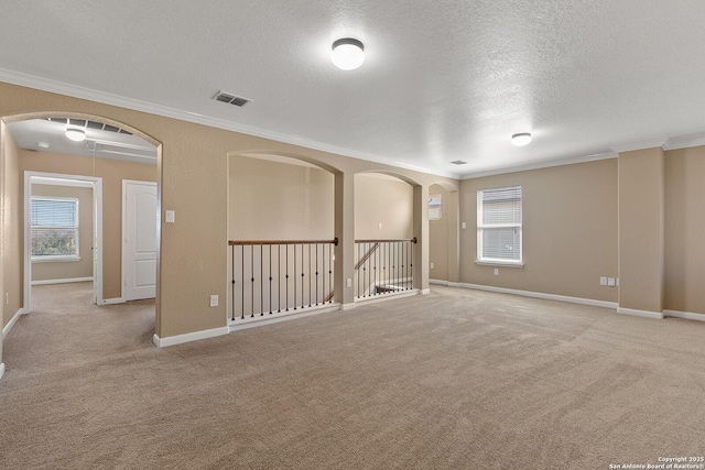 empty room featuring arched walkways, carpet flooring, and ornamental molding