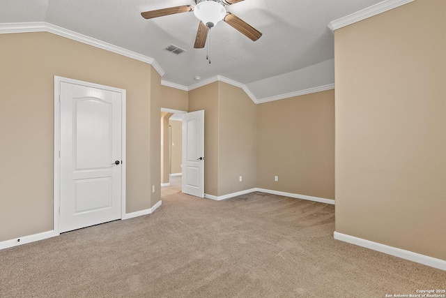 carpeted spare room featuring visible vents, lofted ceiling, baseboards, and ornamental molding