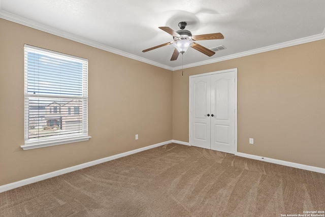 unfurnished bedroom featuring visible vents, crown molding, baseboards, carpet floors, and a closet