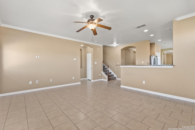 unfurnished room featuring baseboards, visible vents, arched walkways, ceiling fan, and crown molding