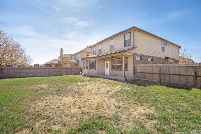 rear view of property with a yard, brick siding, a fenced backyard, and a patio area