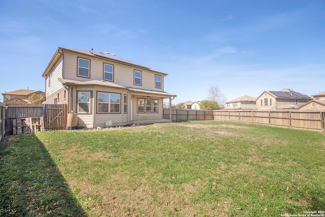 back of house with a lawn, solar panels, and a fenced backyard