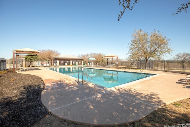 community pool with a gazebo, fence, and a patio area