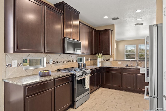 kitchen featuring visible vents, dark brown cabinets, stainless steel appliances, and a sink