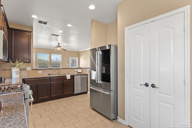 kitchen with tasteful backsplash, visible vents, dark brown cabinets, stainless steel appliances, and a sink