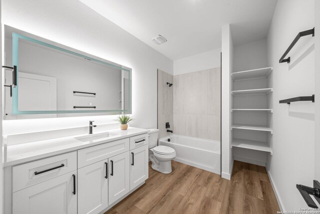 bathroom featuring toilet, wood finished floors,  shower combination, baseboards, and vanity