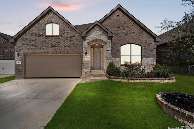 french provincial home featuring brick siding, concrete driveway, and a front lawn