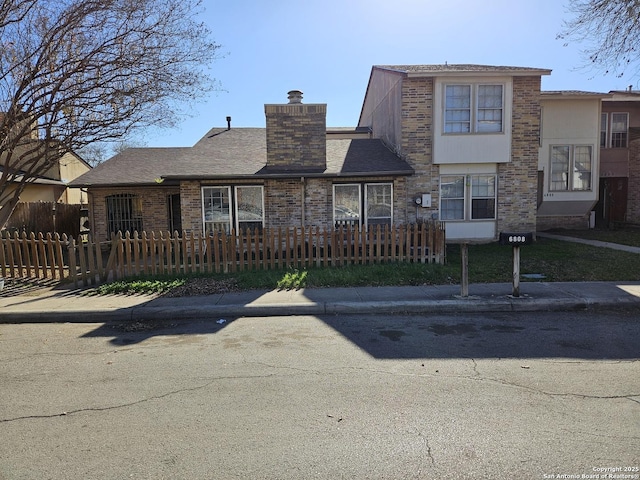 view of front facade featuring a fenced front yard, a chimney, and brick siding