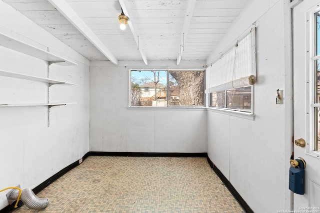 unfurnished room featuring beamed ceiling, light floors, and baseboards