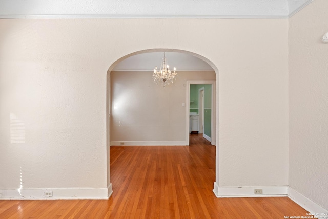 interior space with arched walkways, crown molding, baseboards, and wood finished floors