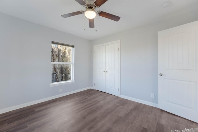 unfurnished bedroom with a closet, baseboards, wood finished floors, and a ceiling fan