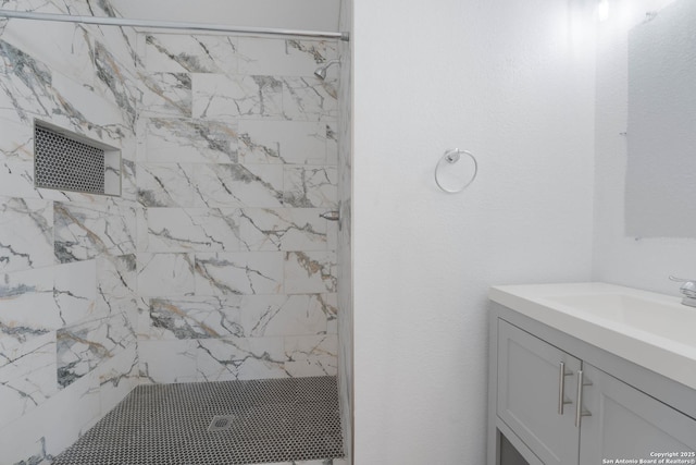 bathroom with tiled shower and vanity