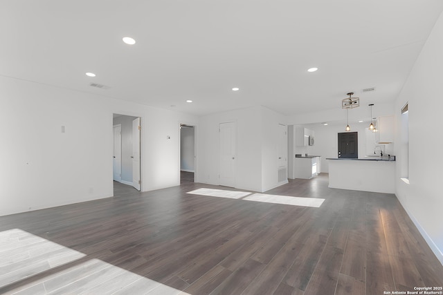 unfurnished living room with recessed lighting, visible vents, dark wood-style floors, and a sink