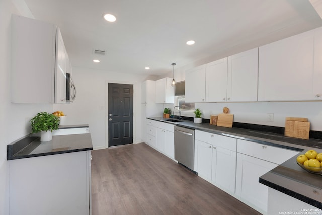 kitchen featuring visible vents, a sink, appliances with stainless steel finishes, white cabinetry, and dark countertops