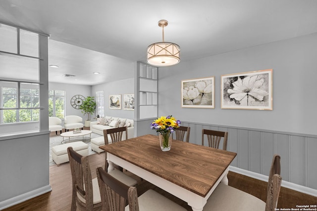 dining space featuring a wainscoted wall, visible vents, and wood finished floors