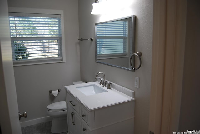 half bathroom featuring vanity, toilet, and baseboards