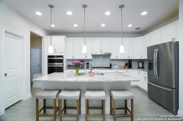 kitchen featuring white cabinets, appliances with stainless steel finishes, and a kitchen bar