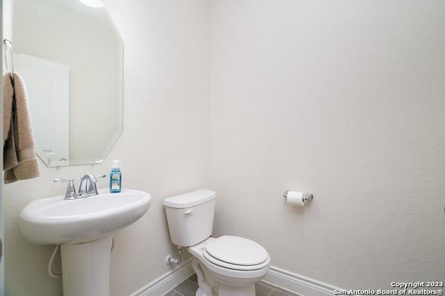 bathroom with baseboards, toilet, and tile patterned flooring