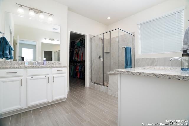 bathroom featuring vanity, wood tiled floor, recessed lighting, a stall shower, and a spacious closet