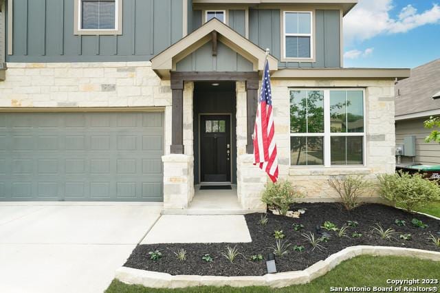 view of exterior entry with stone siding, board and batten siding, and driveway