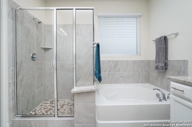 full bathroom with vanity, a bath, and a shower stall