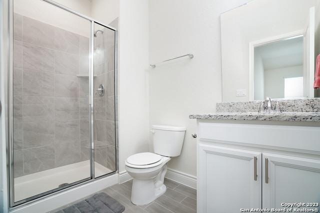 full bath with a stall shower, toilet, vanity, and baseboards