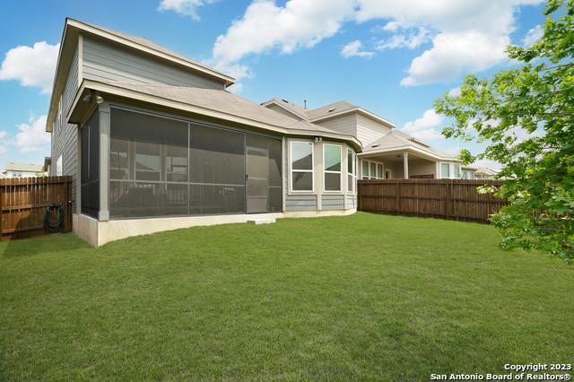 back of property with a yard, fence private yard, and a sunroom