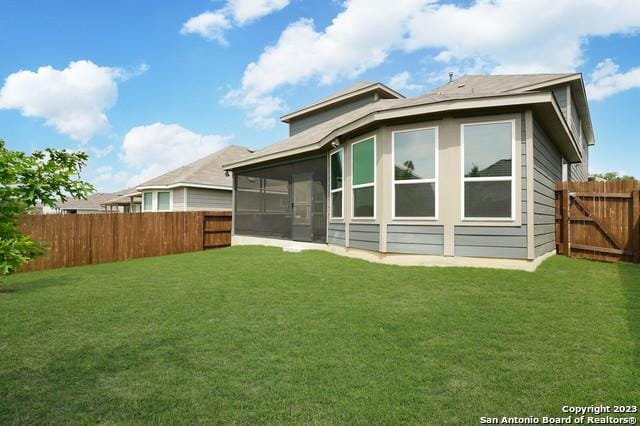 rear view of house with a lawn, a fenced backyard, and a sunroom