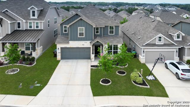 view of front of home featuring board and batten siding, a front lawn, a residential view, a garage, and driveway