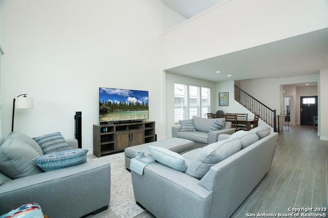 living room featuring a towering ceiling, stairs, and light wood finished floors