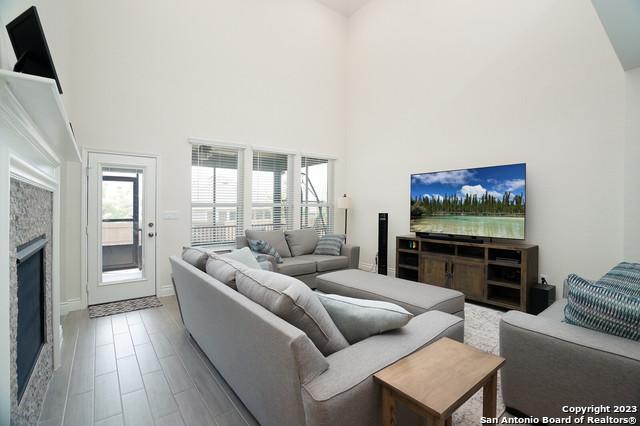 living room featuring a stone fireplace, a towering ceiling, and wood finished floors