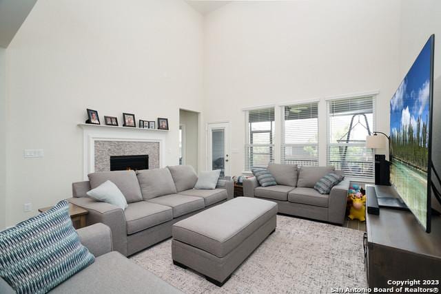 living area featuring a towering ceiling and a lit fireplace