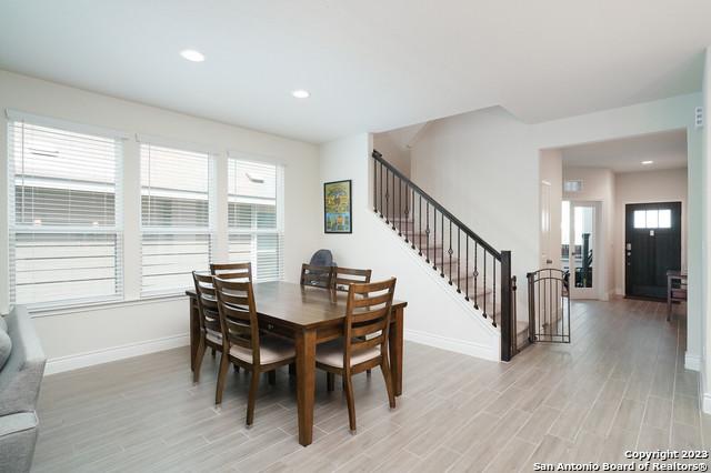 dining room with a wealth of natural light, stairway, and light wood finished floors