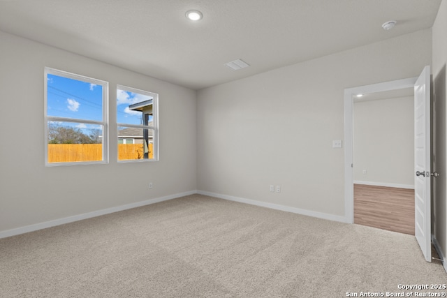 spare room with carpet flooring, visible vents, and baseboards