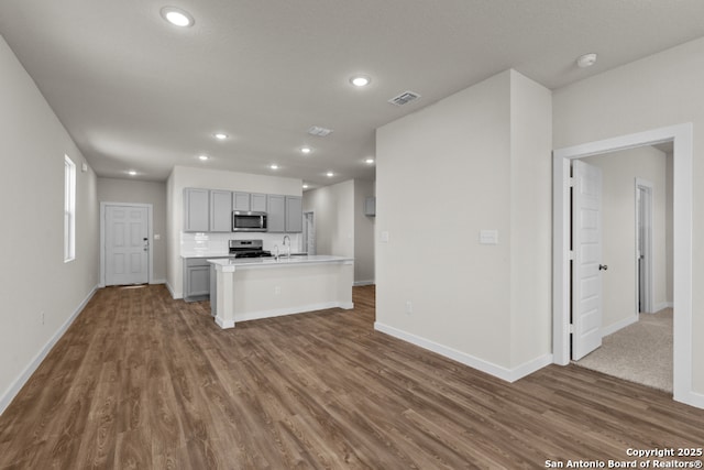 kitchen with gray cabinetry, recessed lighting, appliances with stainless steel finishes, light countertops, and dark wood-style flooring