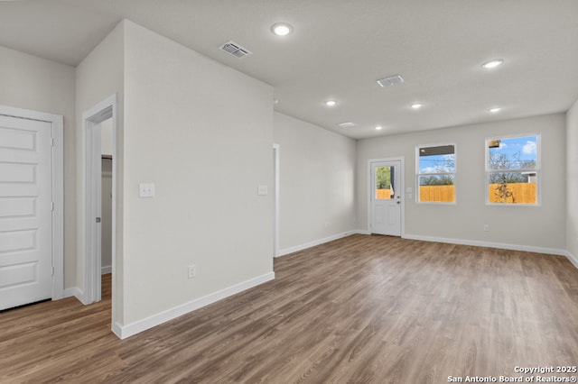 empty room featuring recessed lighting, wood finished floors, visible vents, and baseboards