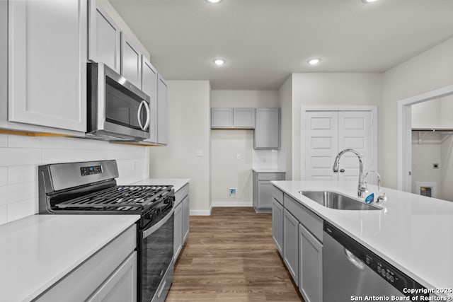 kitchen featuring a sink, appliances with stainless steel finishes, gray cabinetry, and light countertops