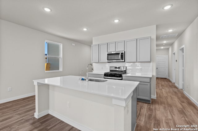 kitchen featuring visible vents, gray cabinets, a sink, stainless steel appliances, and backsplash