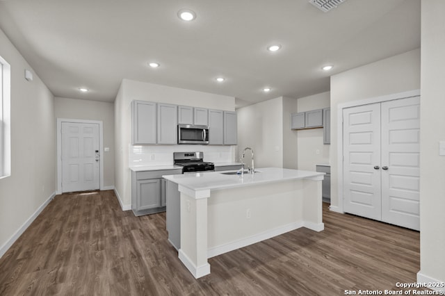 kitchen with a sink, gray cabinetry, dark wood finished floors, and stainless steel appliances