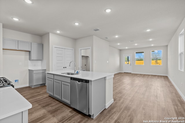 kitchen featuring gray cabinetry, dishwasher, light countertops, wood finished floors, and a sink