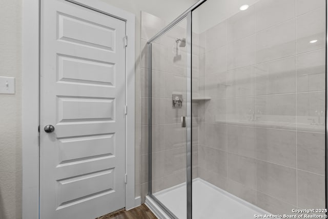 full bathroom featuring a shower stall and wood finished floors