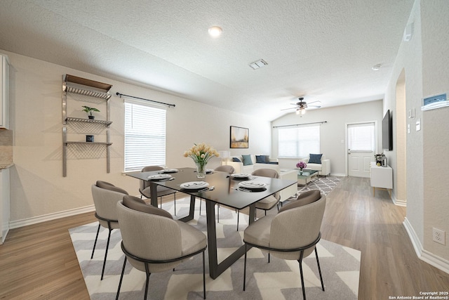 dining area featuring baseboards, a textured ceiling, ceiling fan, and light wood finished floors