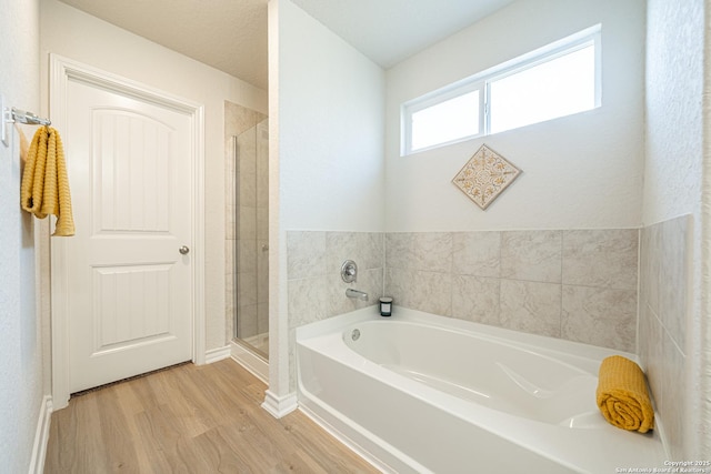 bathroom with wood finished floors, a shower stall, and a bath