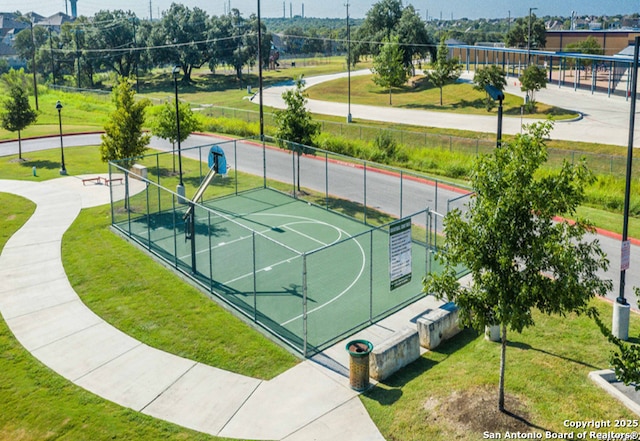 view of basketball court featuring a yard, community basketball court, and fence