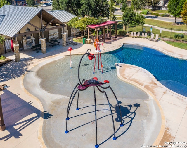 pool featuring a patio, a water play area, and fence