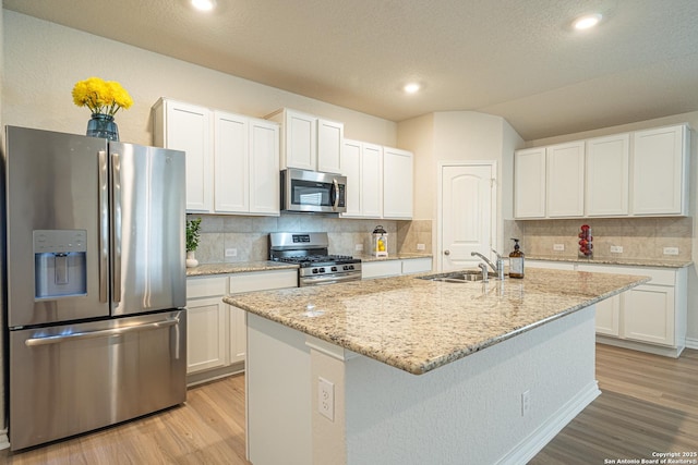 kitchen featuring light wood finished floors, appliances with stainless steel finishes, white cabinetry, and a sink