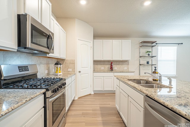 kitchen with a sink, light wood-style floors, white cabinetry, and stainless steel appliances