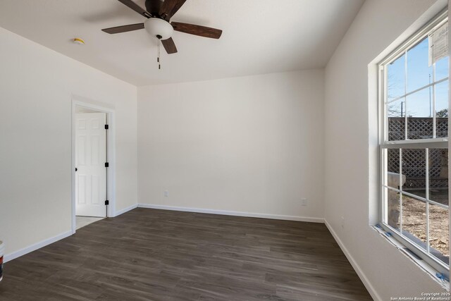 spare room featuring dark wood finished floors, a ceiling fan, and baseboards